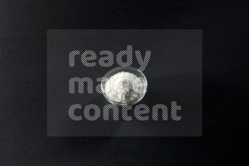 A glass bowl full of desiccated coconut on a black background in different angles