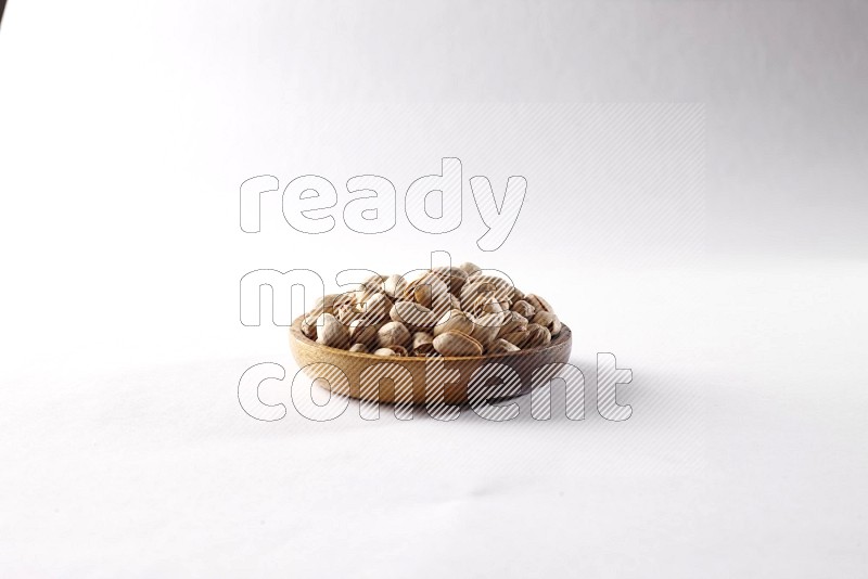 Pistachios in a wooden bowl on white background