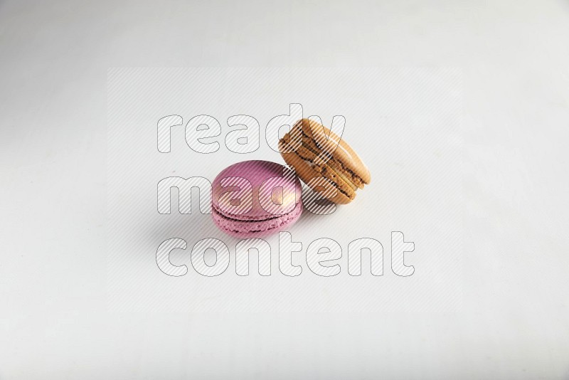 45º Shot of of two assorted Brown Irish Cream, and Purple Strawberry macarons on white background