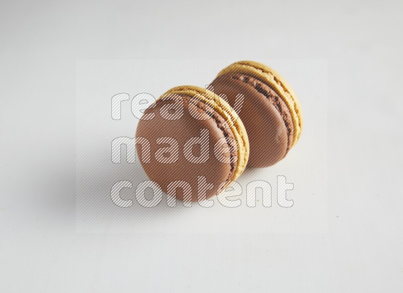 45º Shot of two Yellow and Brown Chai Latte macarons on white background