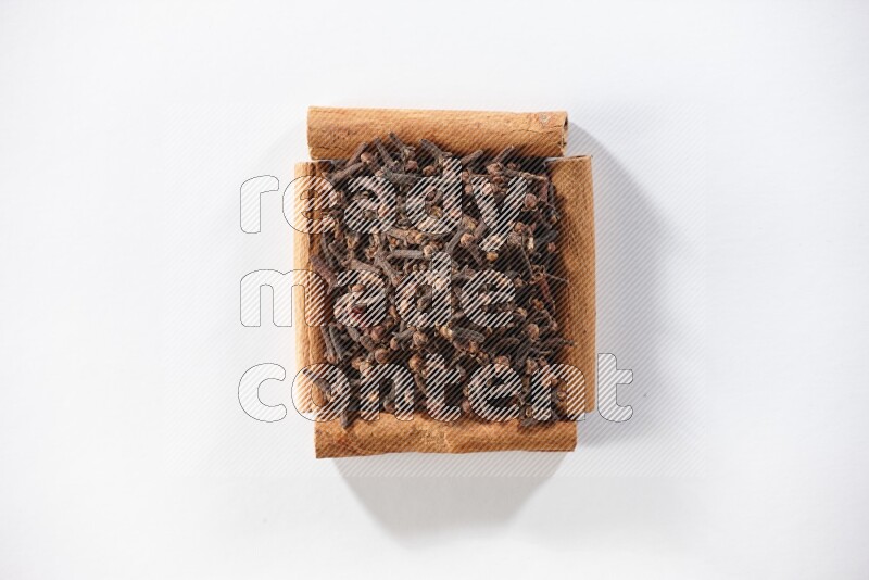 A single square of cinnamon sticks full of cloves on white flooring