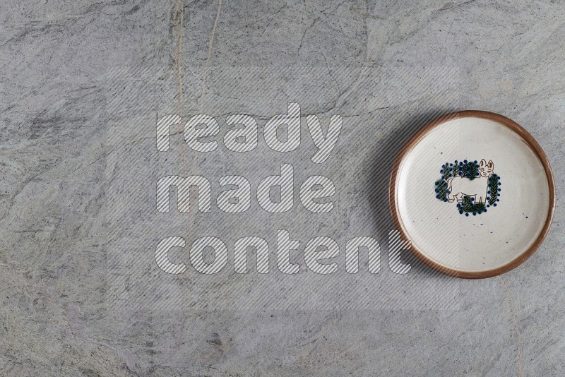 Top View Shot Of A Decorative Pottery Plate On Grey Marble Flooring