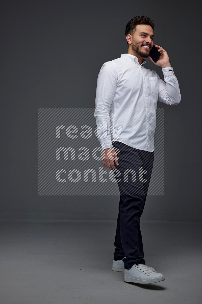 A man wearing smart casual talking in the phone eye level on a gray background