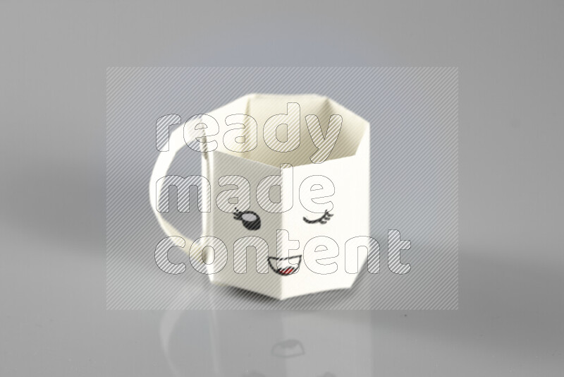 Origami cup on grey background