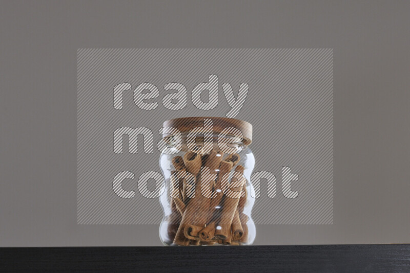 Cinnamon sticks in a glass jar on black background