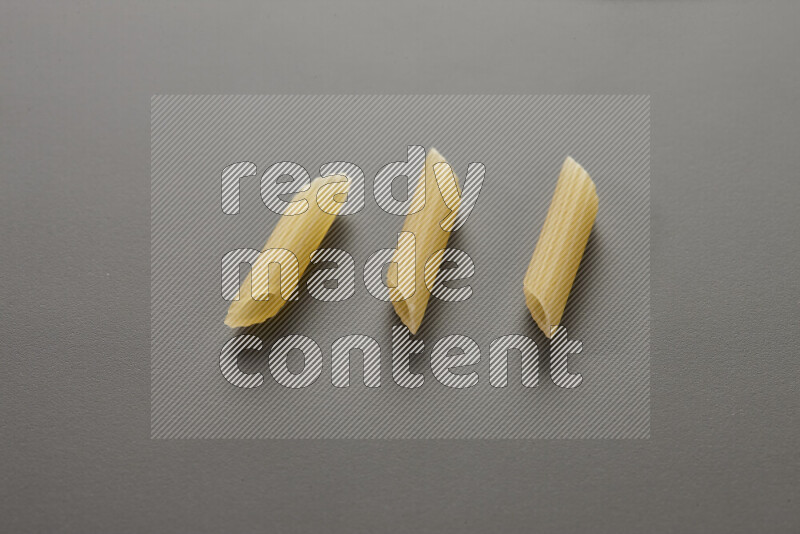 Mini penne pasta on grey background