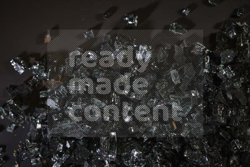 Transparent black fragments of glass scattered on a black background