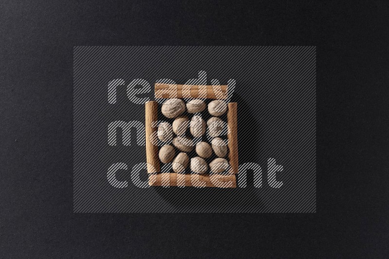 A single square of cinnamon sticks full of nutmeg on black flooring