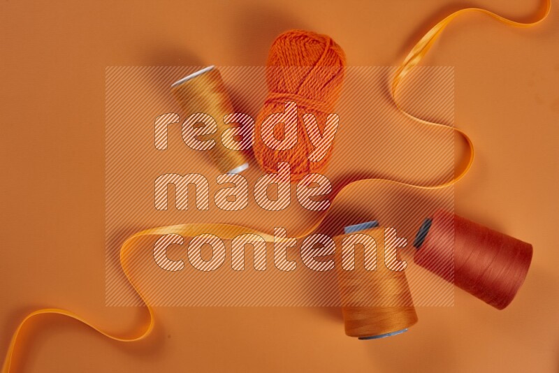 An orange collection of sewing and tailoring tools arranged on a orange background