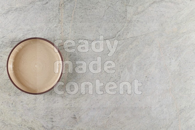 Top View Shot Of A Beige Pottery Oven Plate On Grey Marble Flooring