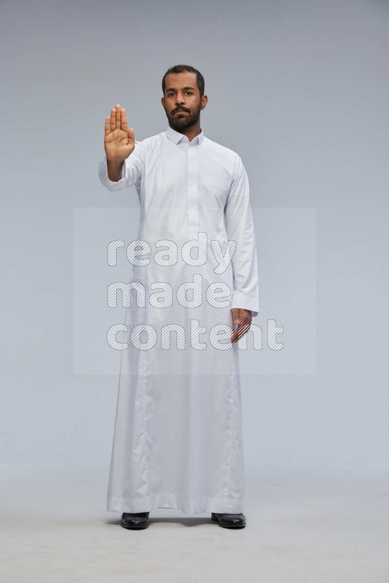 Saudi man Wearing Thob standing interacting with the camera on Gray background