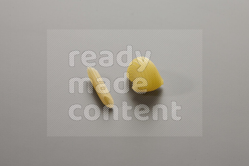 Mini penne pasta with other types of pasta on grey background