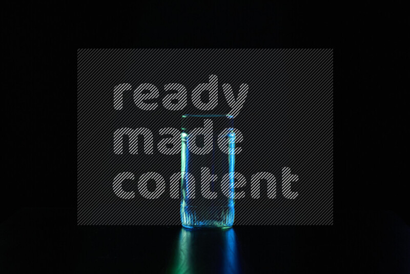 Glassware with rim light in blue and green against black background