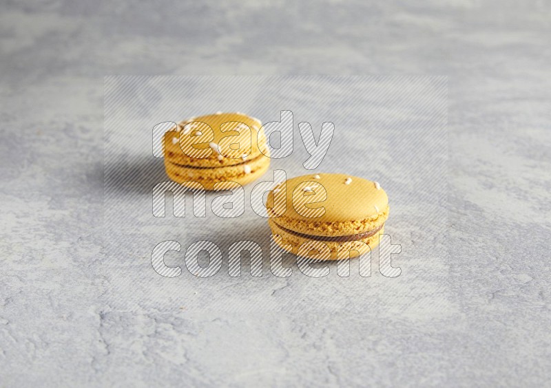 45º Shot of two Yellow Piña Colada macarons  on white  marble background