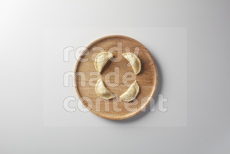 Four Sambosas on a wooden round plate on a white background