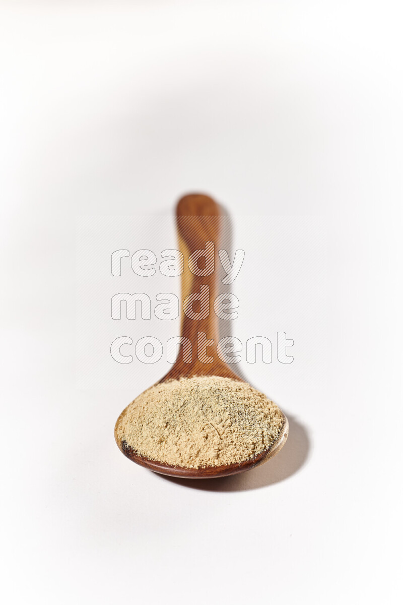 A wooden ladle full of ground ginger powder on white background