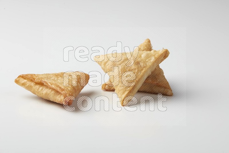Three fried sambosas on a white background
