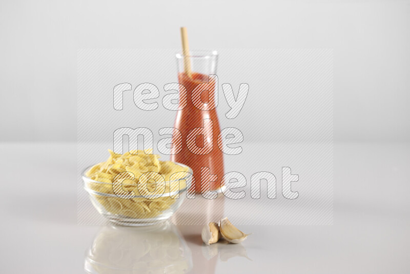 معكرونة مع صلصة طماطم مع مكونات متنوعة من الطماطم والثوم والريحان والفلفل الأحمر والفلفل الأسود والفلفل الأبيض وأوراق الغار والهيل وسنابل القمح على خلفية رمادية