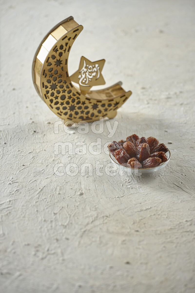 A wooden golden crescent lantern with different drinks, dates, nuts, prayer beads and quran on white background
