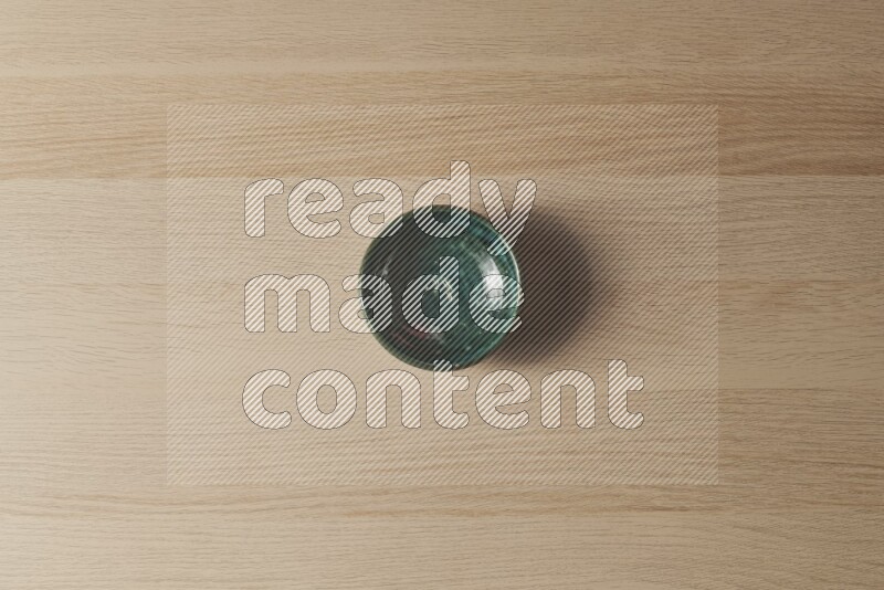 A dark green pottery bowl on light wooden background