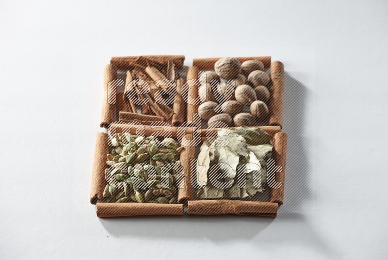 4 squares of cinnamon sticks full of nutmegs, bay laurel leaves, cardamom and cinnamon on white flooring