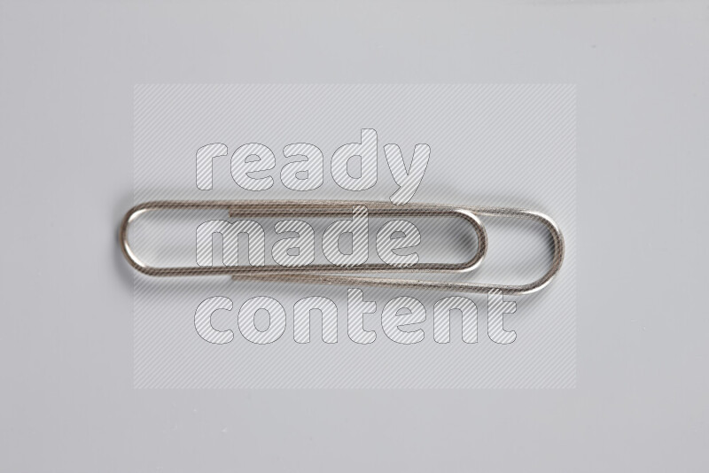 Silver paper clips isolated on a grey background