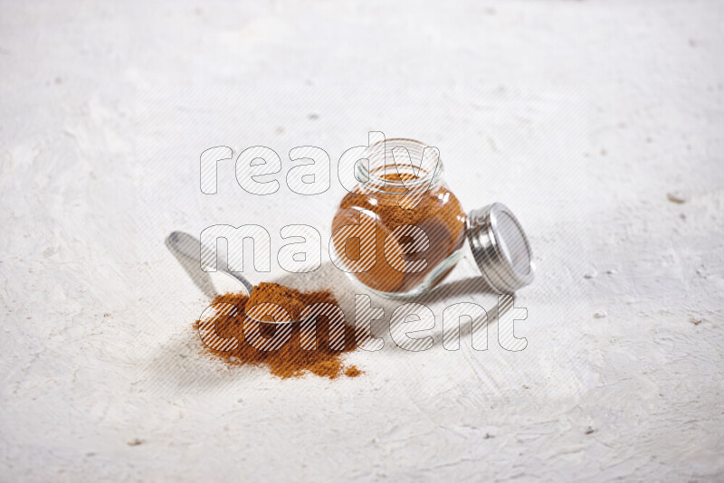 A glass jar full of ground paprika powder on white background