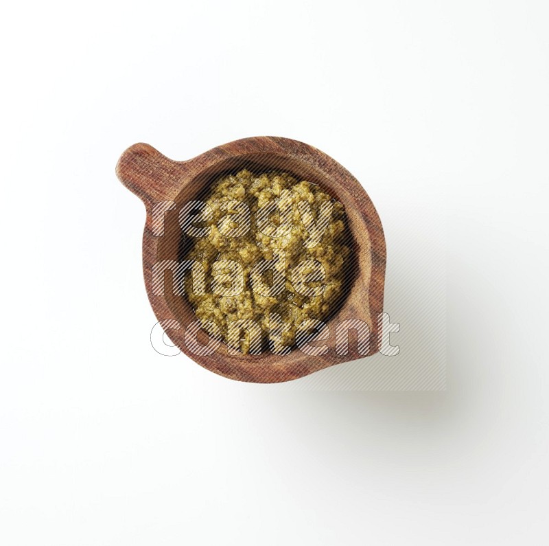 medium brown wood bowl filled with pesto paste on a white table top