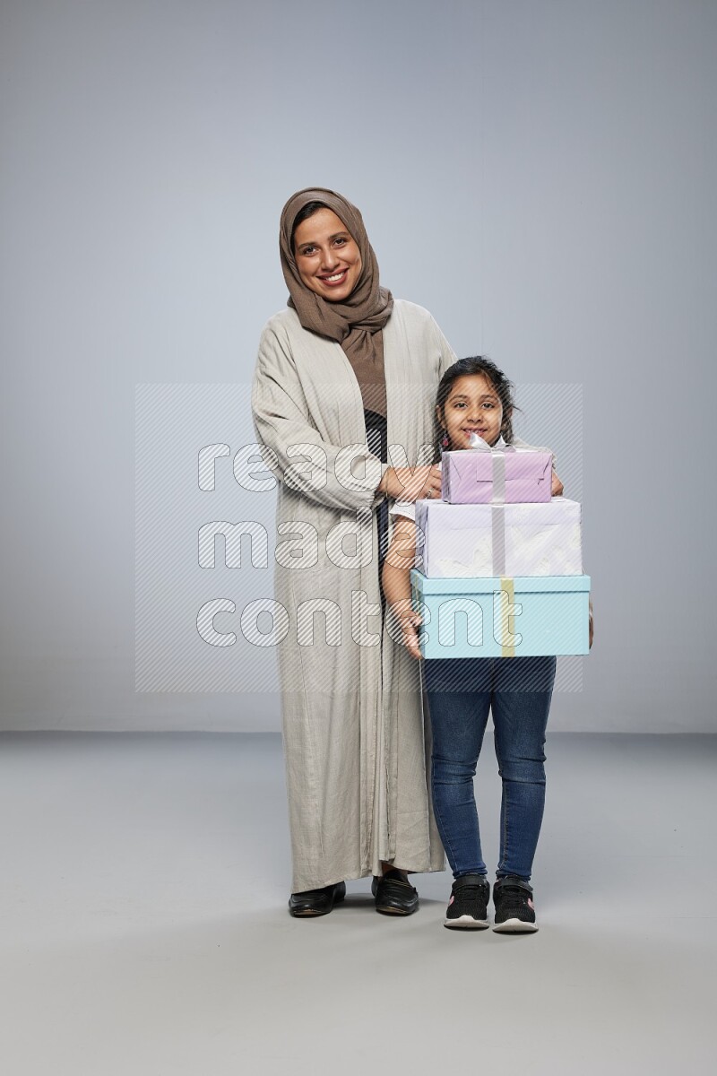 A girl giving a gift to her mother on gray background