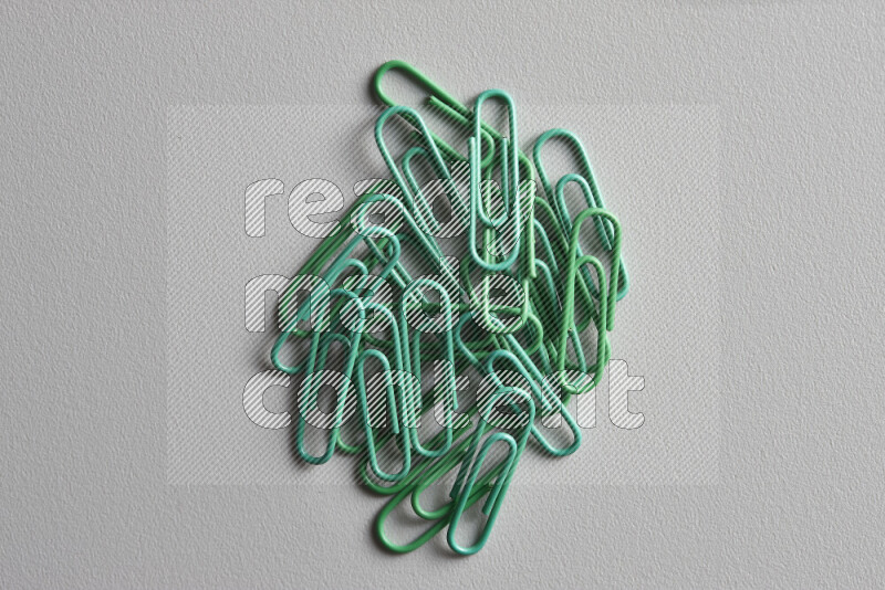 Green paper clips isolated on a grey background