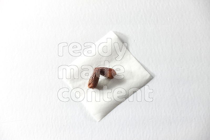Two dried dates on a piece of paper on a white background in different angles