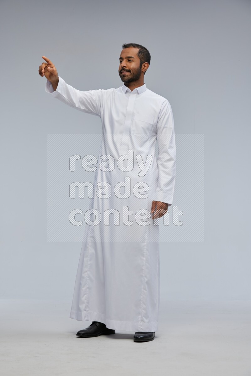 Saudi man Wearing Thob standing interacting with the camera on Gray background