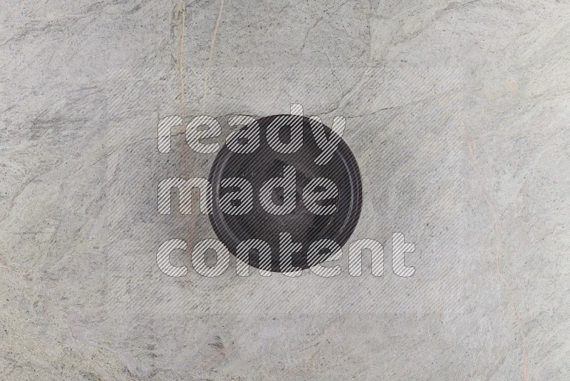 Top View Shot Of A Black Pottery Oven Plate On Grey Marble Flooring