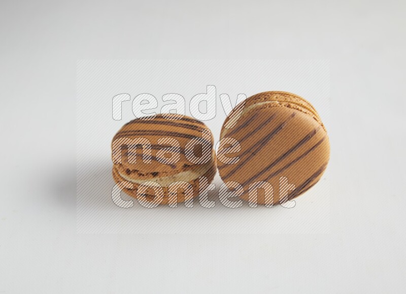 45º Shot of two light brown  Almond Cream macarons on white background