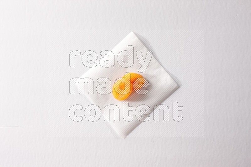 Two dried apricots on a piece of paper on a white background in different angles