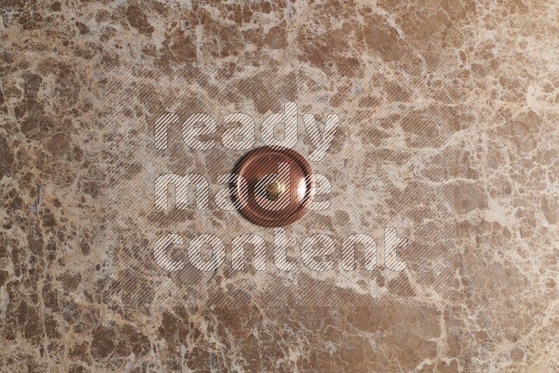 A small copper pot on beige marble background