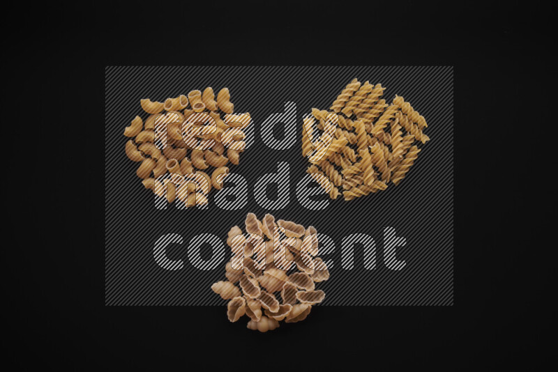 Different pasta types in bunches on black background