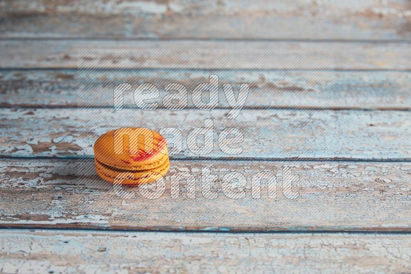 45º Shot of Orange Exotic macaron on light blue wooden background
