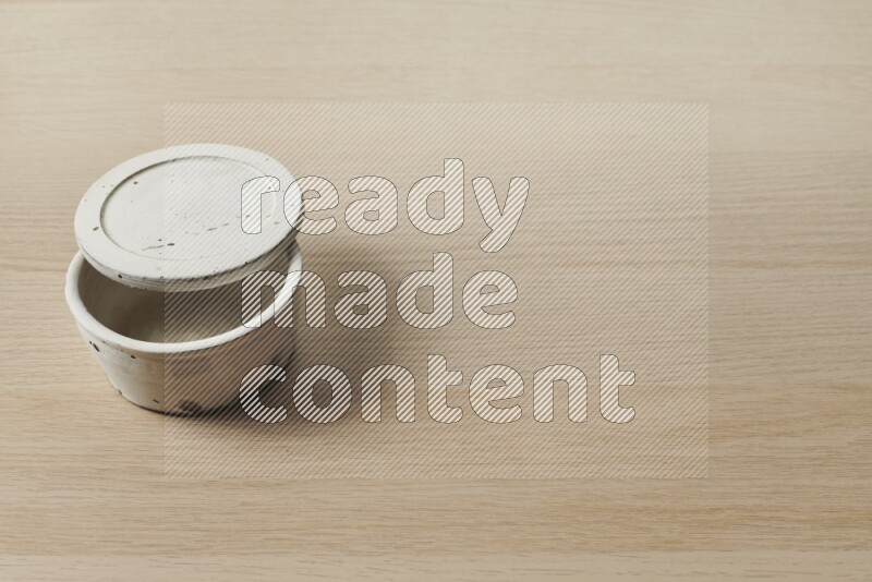 A white pottery bowl on light wooden background
