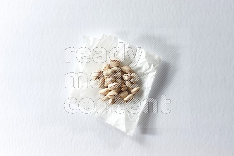 Pistachios on a crumpled piece of paper on a white background in different angles