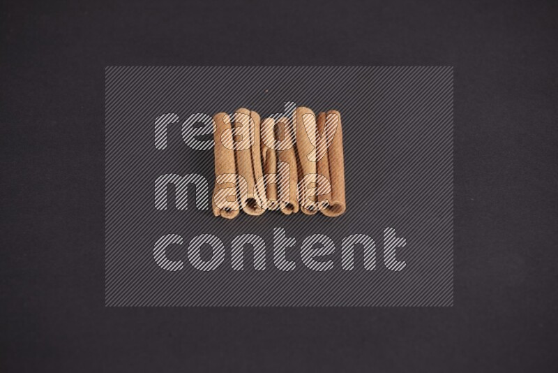 Cinnamon sticks stacked on black flooring
