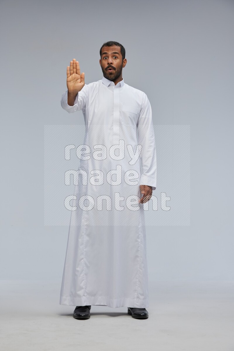 Saudi man Wearing Thob standing interacting with the camera on Gray background