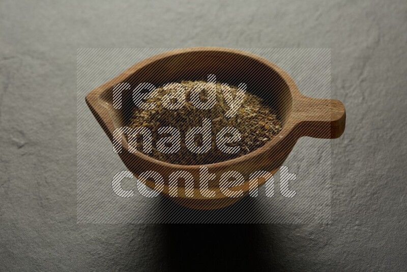 wooden round sauce bowl filled with herbs on grey textured countertop