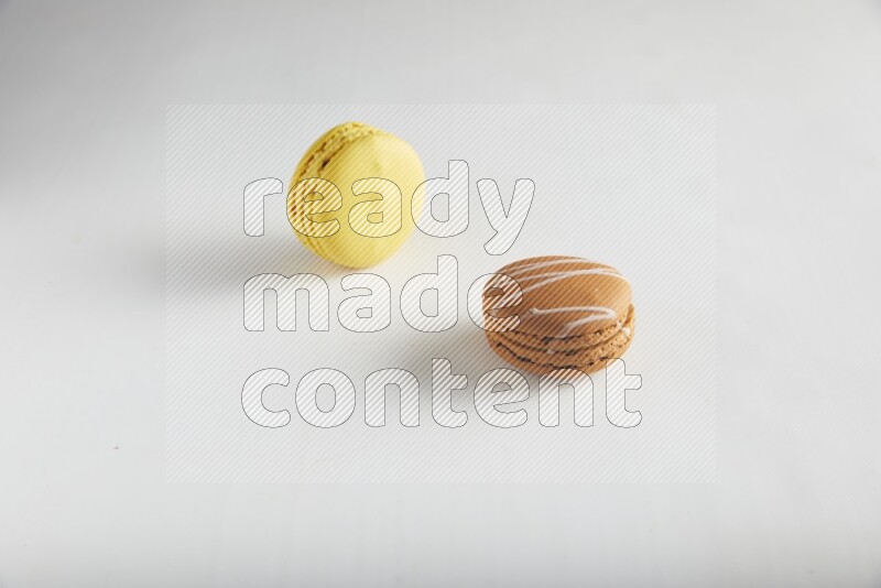 45º Shot of of two assorted Brown Irish Cream, and Yellow Lemon macarons on white background