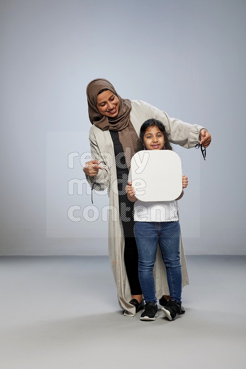 Mom and daughter standing holding social media sign on gray background