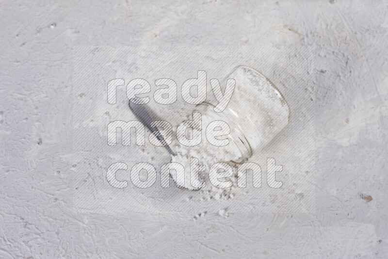 A glass jar full of coarse sea salt crystals on white background