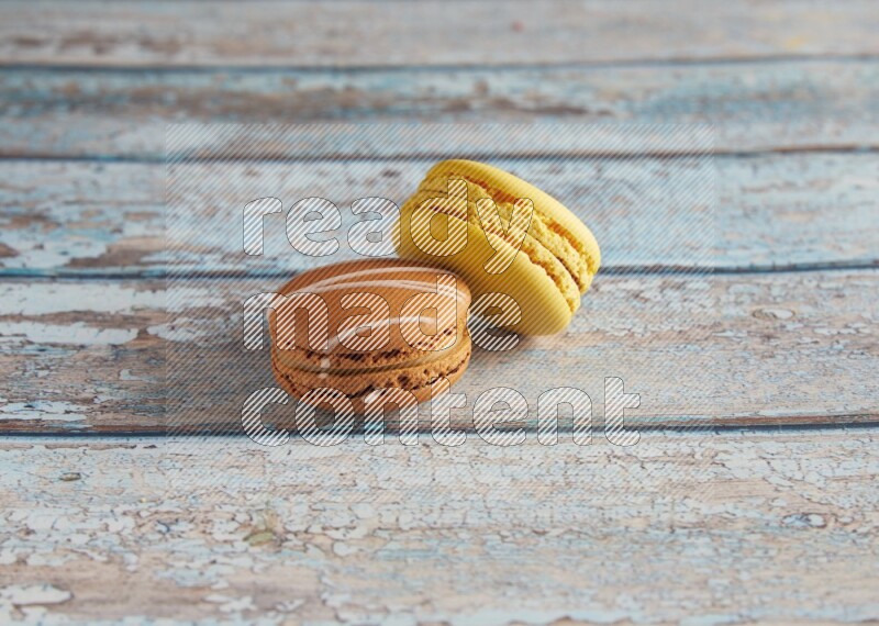 45º Shot of of two assorted Brown Irish Cream, and Yellow Lemon macarons on light blue background