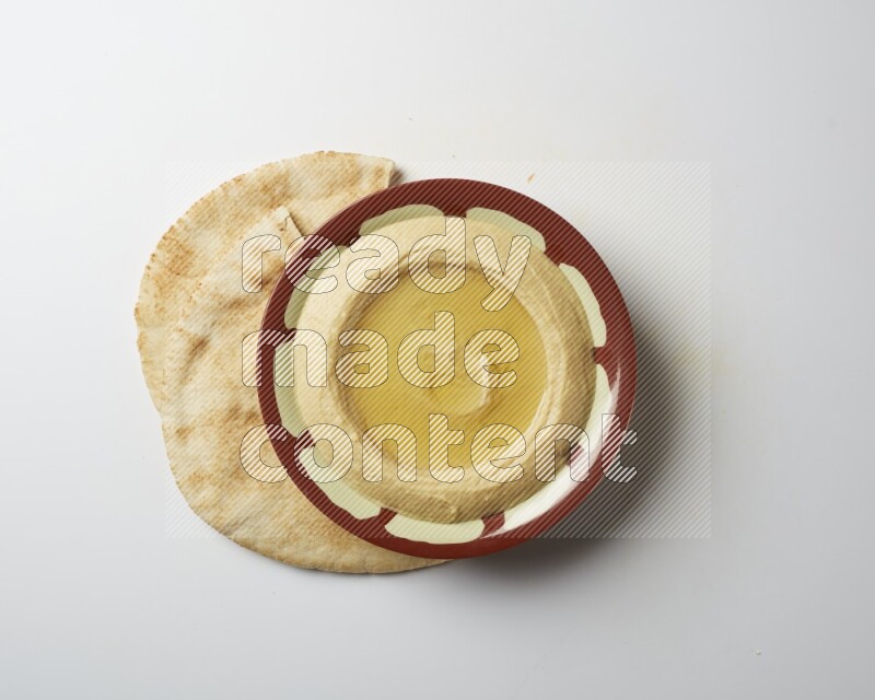 Hummus in a traditional plate garnished with olive oil on a white background