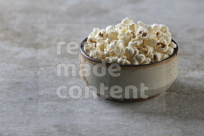 popcorn in multi-colored pottery bowl on a grey textured countertop