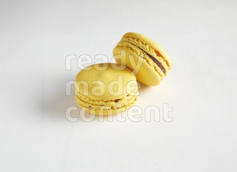 45º Shot of two Yellow Lemon macarons on white background